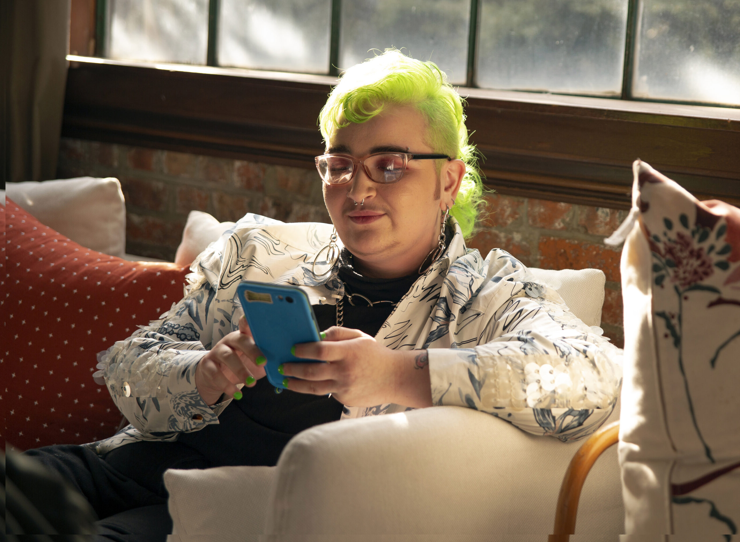 A genderqueer person looking at their phone