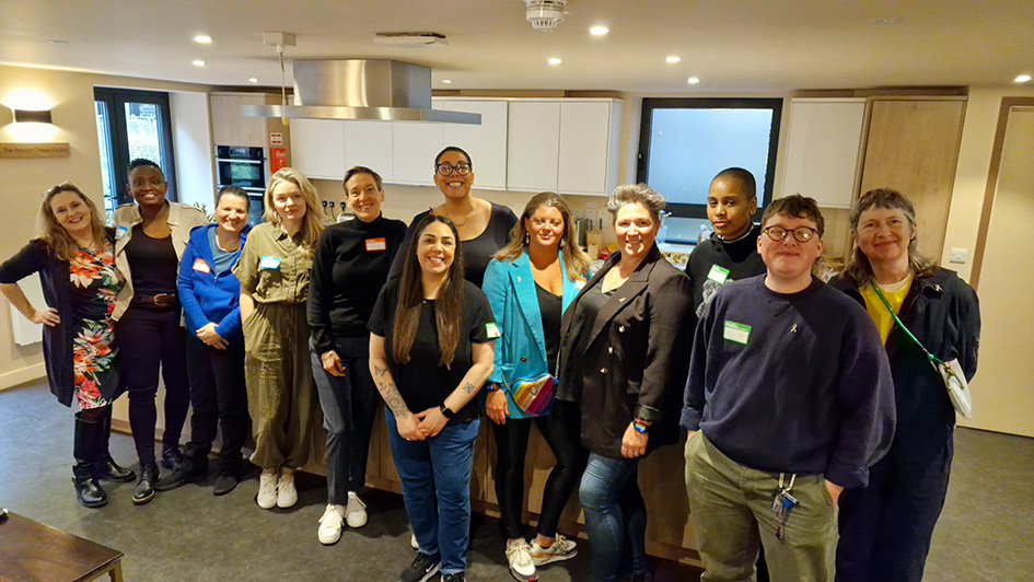 A group of attendees to an LGBTIQ+ breast cancer support group standing in a bright and modern kitchen style space