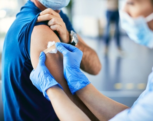 Nurse applying a bandage on a patient's arm after giving a vaccination.